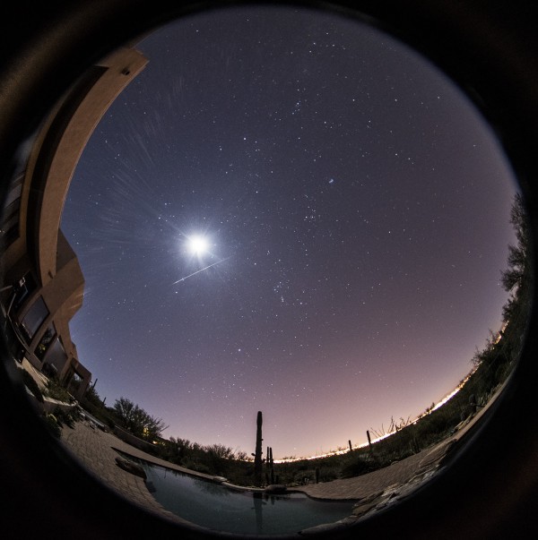 Whole-sky panorama with stars, moon, thin white streak.