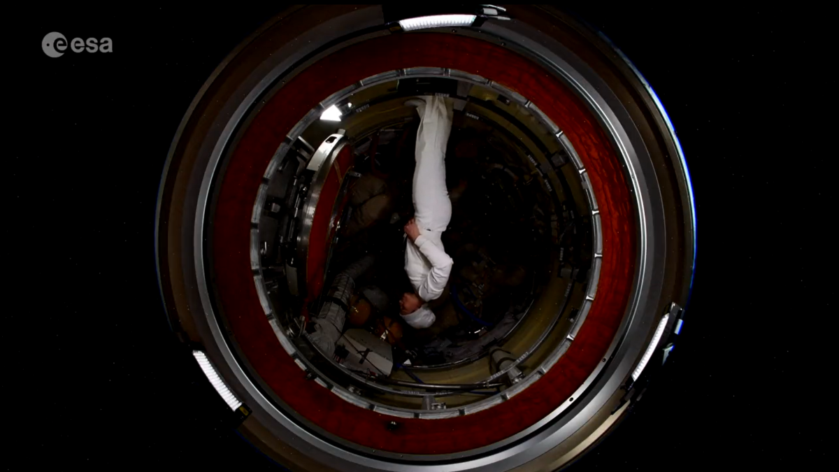 astronaut samantha cristoforetti upside down in a space station module in a white suit
